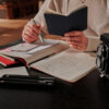 Person-writing-on-Moleskine-Cahier-Journal-on-a-desk